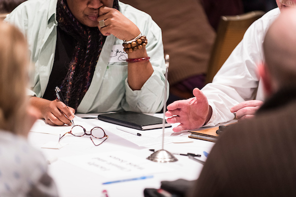 Discussion at a table with a close up of view of papers and someone gesturing
